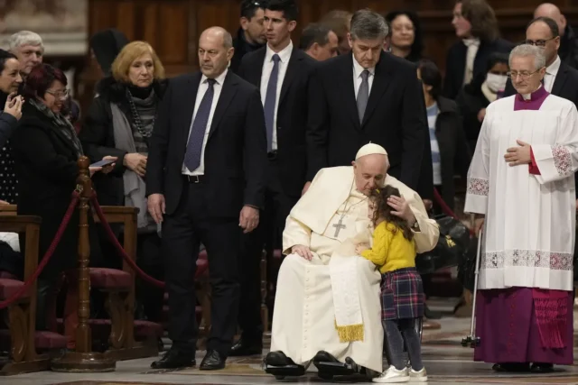 el papa francisco besa a una niña cuando llega para presidir las primeras vísperas