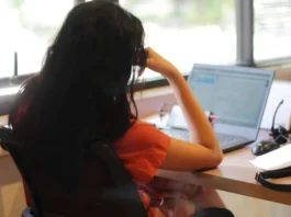 1365 a-young-woman-is-sitting-in-an-office-seen-from-behind-holding-her-head-while-doing-her-work-free-photo
